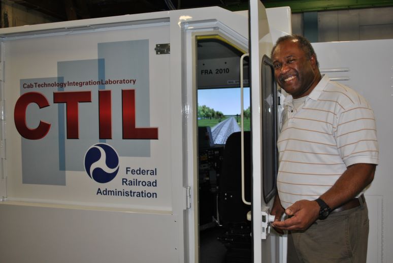 Mike Jones stands outside of the CTIL with the door ajar, making part of the control stand and display visible